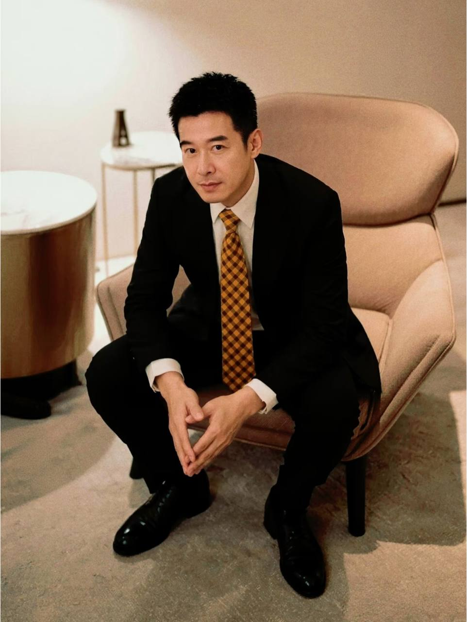 睿心漫語創辦人林承睿身穿西裝，坐在扶手椅上。